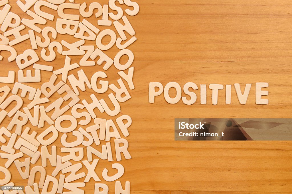 Word positive made with block wooden letters Word positive made with block wooden letters next to a pile of other letters over the wooden board surface composition 2015 Stock Photo