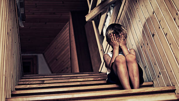 Depressed little boy crying. Depressed  poor child sitting on stairs. The boy is crying and hiding his face in hands. child abuse photos stock pictures, royalty-free photos & images