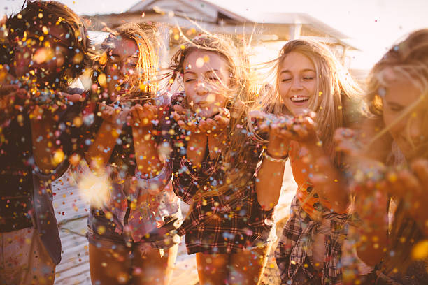 istock Teens celebrating with colourful confetti outside on summer evening 472708014