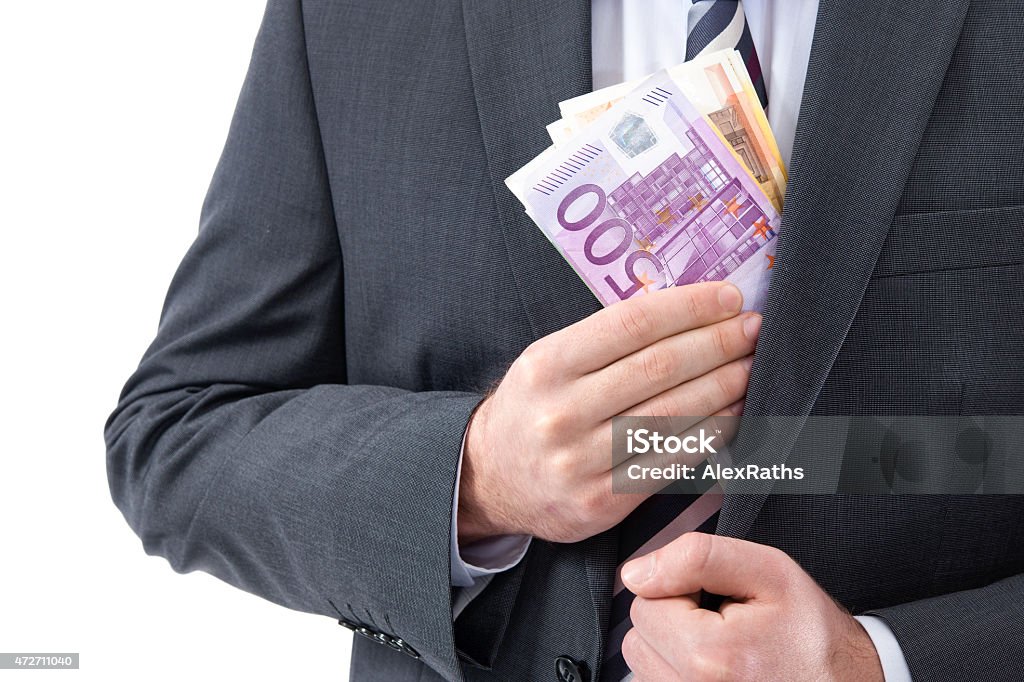 bribery concept A businessman in a suit putting money in his pocket 2015 Stock Photo