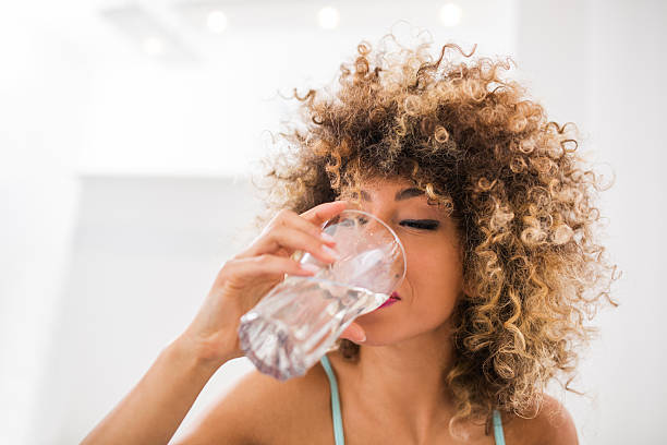 thirsty african american woman drinking water. - drinking water stockfoto's en -beelden