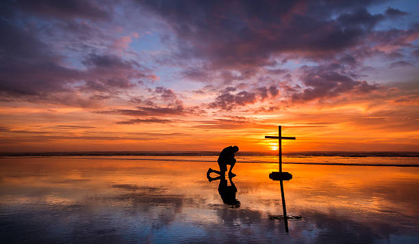 Colors of Prayer Wonderful reflection on a beach at sunset, with a man kneeling by it. kneeling stock pictures, royalty-free photos & images