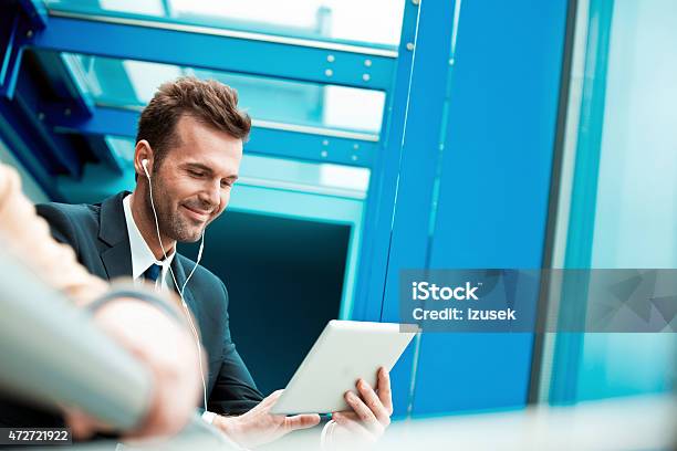 Businessman Wearing Earphone Using A Digital Tablet Stock Photo - Download Image Now
