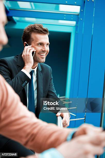 Businessman Talking On Smart Phone In An Office Hall Stock Photo - Download Image Now