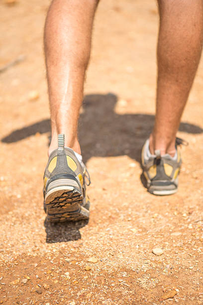 istock Man's legs walking on dirt ground 472724380