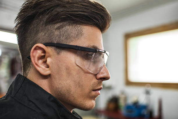 Close up of young mechanic with protective eyewear looking away.