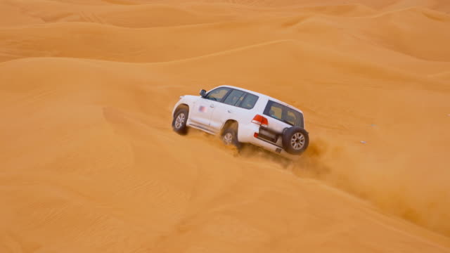 SLO MO Off road car driving over a sand dune