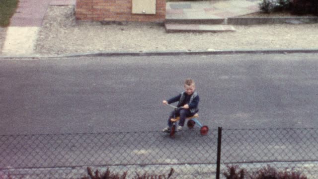 Little boy riding trike on street (vintage 8mm film)