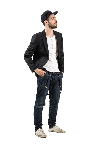 Young confident fashion model with baseball cap looking up. Full body length portrait isolated over white background