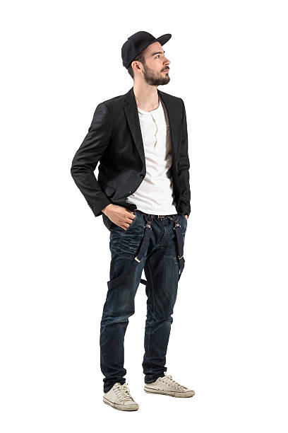 Young confident fashion model with baseball cap looking up Young confident fashion model with baseball cap looking up. Full body length portrait isolated over white background man standing profile stock pictures, royalty-free photos & images