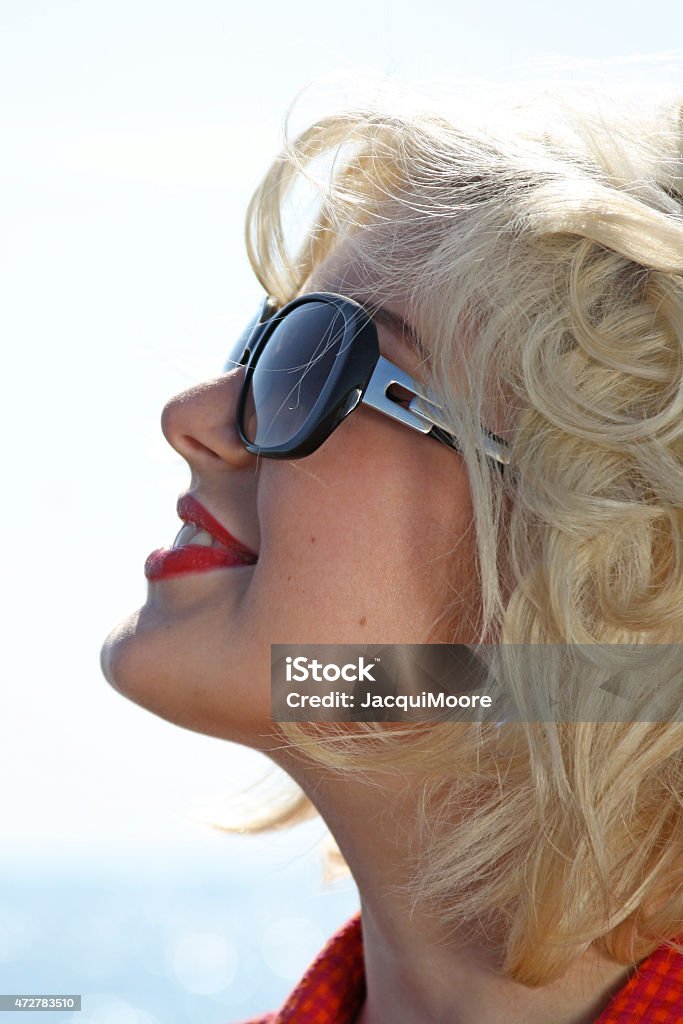 Stunning blonde haired teenage girl at the beach Portrait of a beautiful young woman retro styled wearing sunglasses 20-29 Years Stock Photo