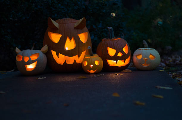istock Varied sizes of lit carved pumpkins 472785892