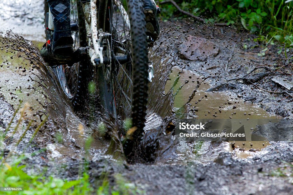 Mountain Bike Mud Puddle A man competing in a mountain bike race rides through a deep puddle on a muddy trail. Mountain Bike Stock Photo