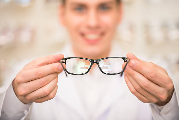 istock Optician holding out a pair of black glasses 472790480