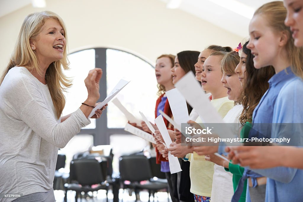 Children In Singing Group Being Encouraged By Teacher Music Stock Photo