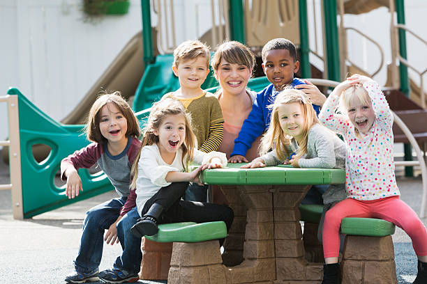 istock Teacher with preschoolers on playground laughing 472795922