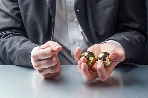 male manager with metallic anti-stress balls in his hands on the workplace