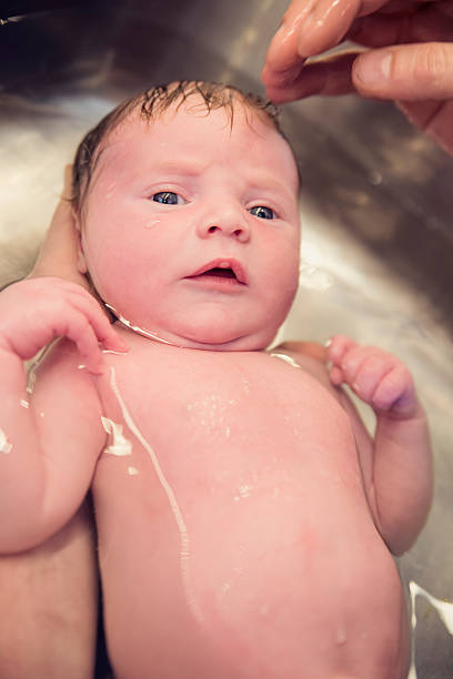 istock Newborn baby bathing in kitchen sink with dad hands. 472805388