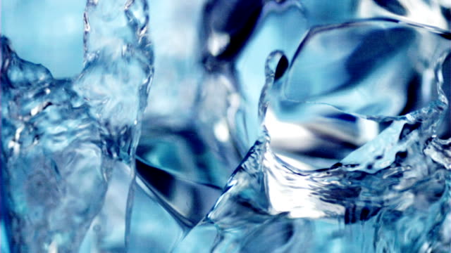 Pouring water into a glass with cubes of ice.
