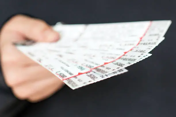 Tickets to a show / event in a hand with a black background.