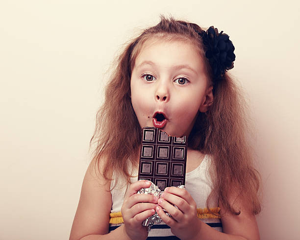 istock Surprised girl with open mouth holding chocolate and looking 472813374