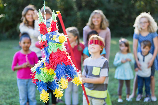 istock Group of children with boy hitting pinata 472823180