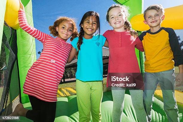 Four Multiethnic Children Playing On Bouncy Castle Stock Photo - Download Image Now