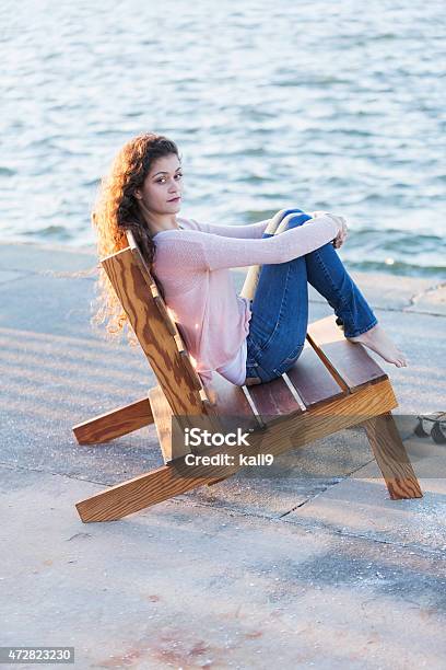 Young Woman Sitting By The Water On A Pier Stock Photo - Download Image Now - 20-29 Years, 2015, Adult