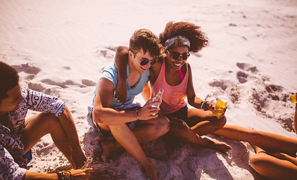 istock Mixed race couple drinking beer on beach on summer day 472830454