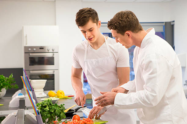 студент-повар обучение с преподавателем - chef trainee cooking teenager стоковые фото и изображения