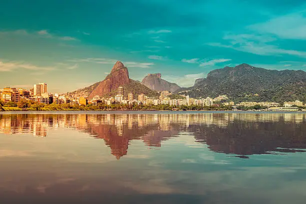 Sunrise over mountains in Rio de Janeiro with water reflection and light leak, Brazil