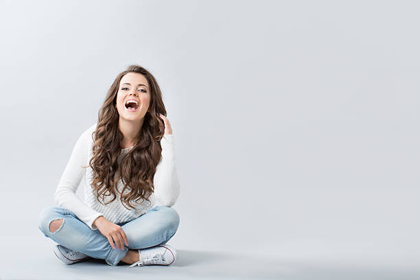 Girl with long wavy hair sitting on the floor and enjoys