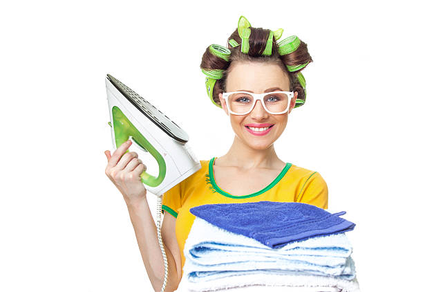 Smile woman holding iron and towels. stock photo