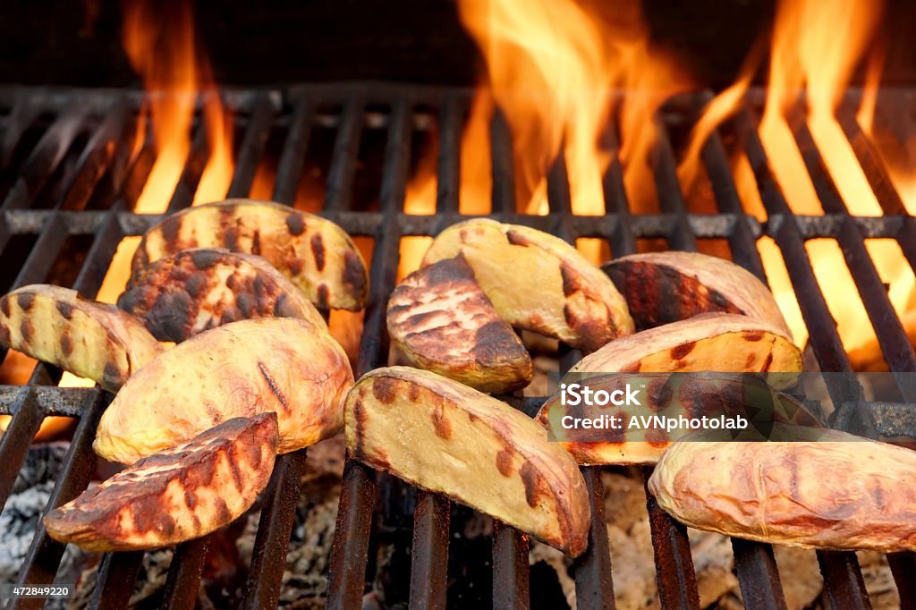 Big Slice Of Potatoes On Hot BBQ Grill Big Slice Of Village-Style Potatoes On Hot BBQ Charcoal Grill. Flames of Fire In The Background. Tasty Snack For Outdoor Summer Barbecue Party Or Picnic. 2015 Stock Photo