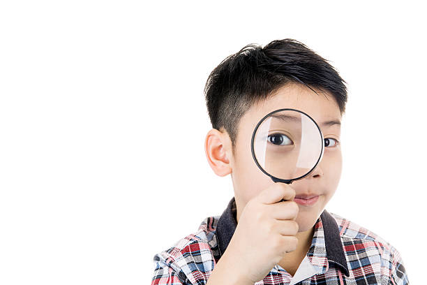 young asian child looking through a magnifying gla stock photo