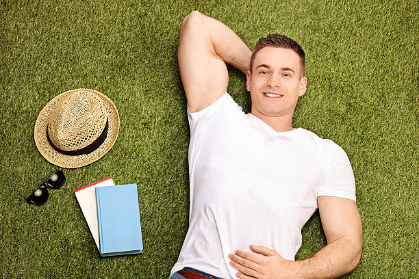 istock Carefree young man lying on grass 472860048