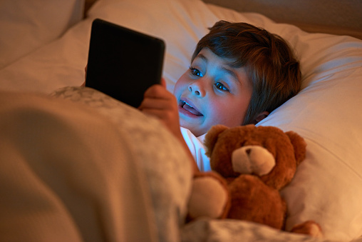 Shot of a young boy using a digital tablet while lying in bedhttp://195.154.178.81/DATA/i_collage/pi/shoots/783045.jpg