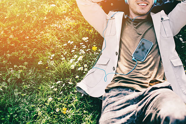istock Young man with headphones lying down in the grass 472861476