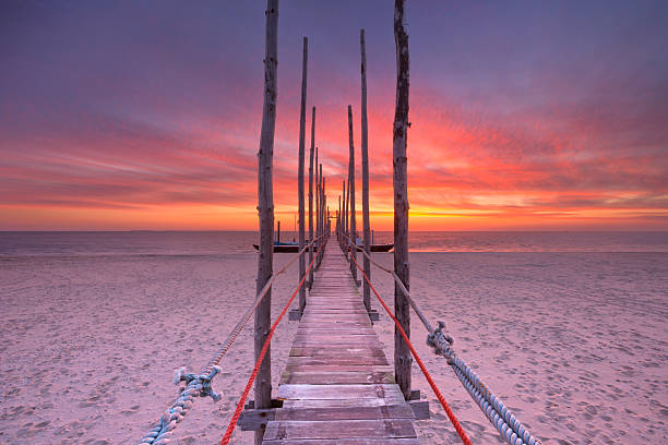Spectacular sunrise colours over a jetty on a beach on the island of Texel in The Netherlands.