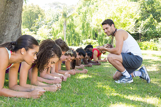 istock Fitness group planking in park with coach 472869176