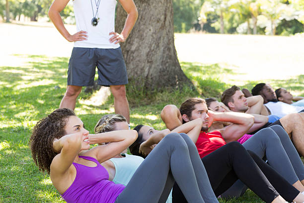 istock Fitness group doing sit ups in park with coach 472869180