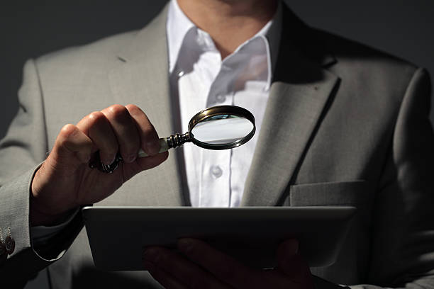 istock Businessman holding magnifying glass and digital tablet 472876242