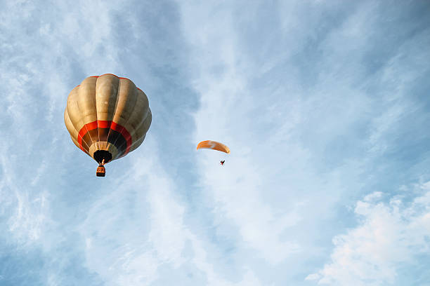 hot air balloon and a paraglider next to it stock photo