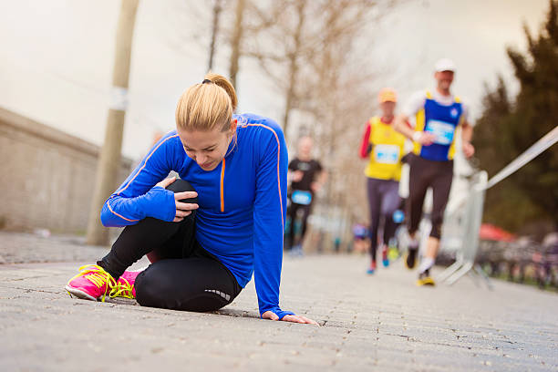 Female runner sitting on sidewalk clutching injured knee Young woman running in the city competition falling on the ground bratislava photos stock pictures, royalty-free photos & images