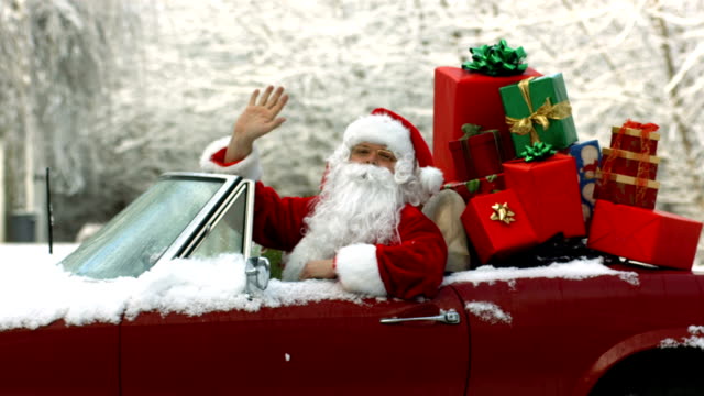 Santa Claus sitting in convertible piled with Christmas gifts