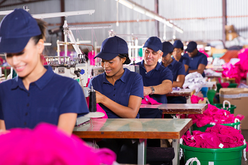 group multiracial factory workers sewing in clothing factory