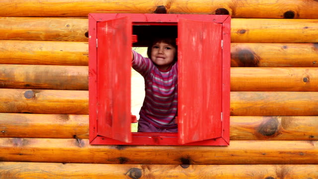 Cheerful little girl in the wooden hut