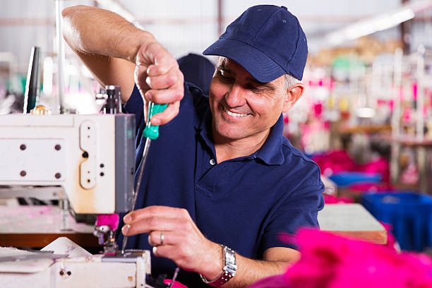 istock senior mechanic repairing industrial sewing machine 472904042