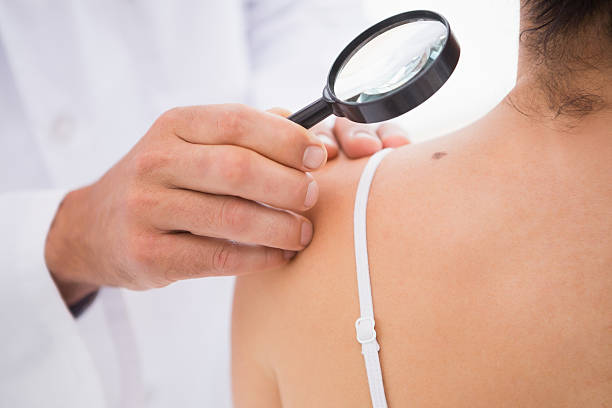 istock Doctor examining patient with magnifying glass 472909362