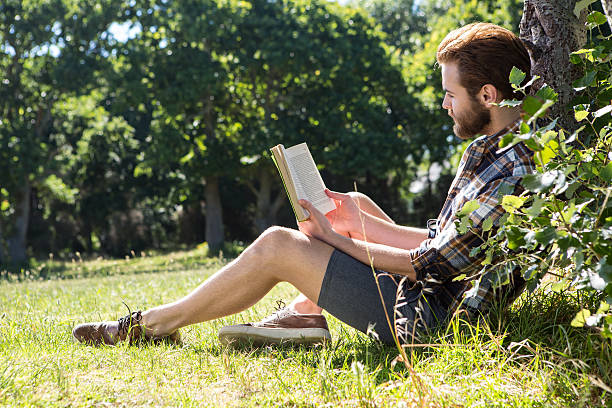 istock Handsome hipster reading book in park 472910442
